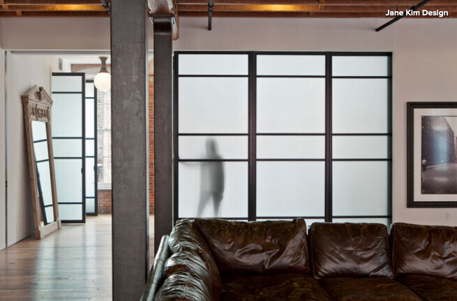 Living room with brown leather sofa and frosted glass partition with metal supports.