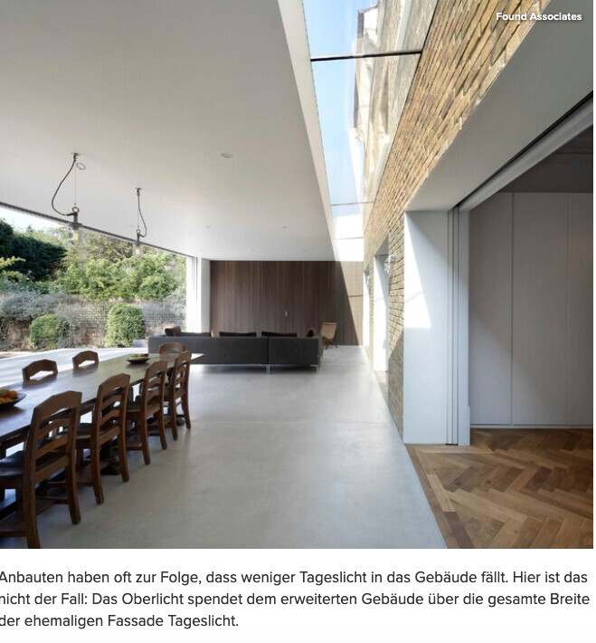Large wooden table with chairs in open living area, view of garden.