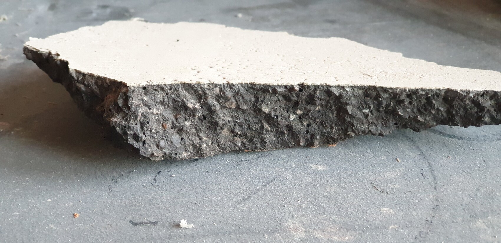 Block of concrete with smooth top surface and porous coarse-grained underside
