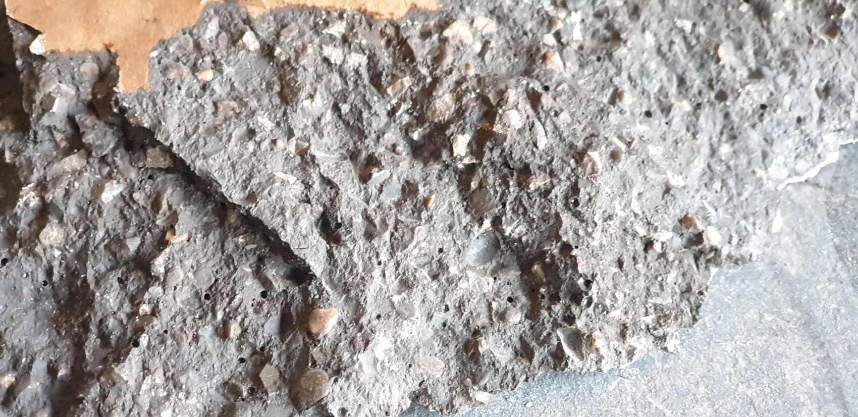 Coarse gray concrete surface with gravel and dust, close-up