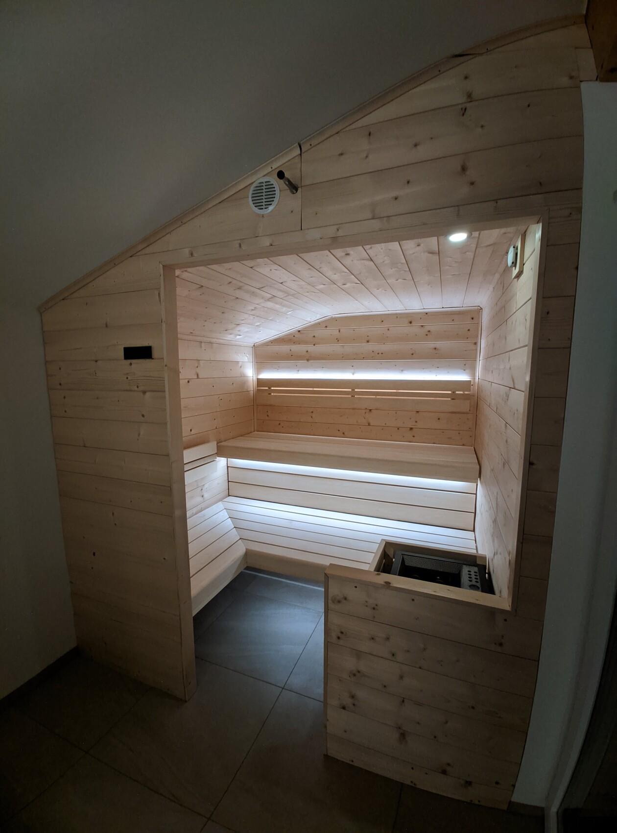 Interior view of a wood sauna with seating benches and a heating stove