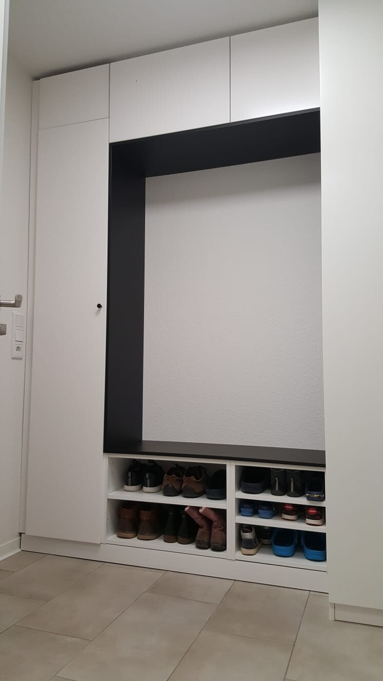 White built-in closet with black open niche and shoe rack below.