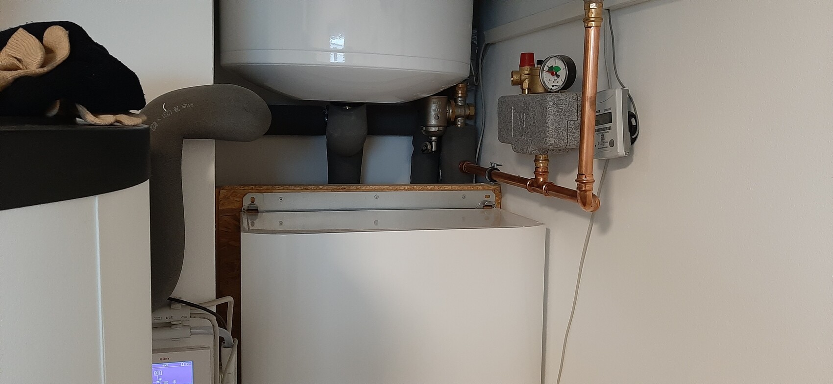 Small heating room: hot water tank, copper pipes, pressure reducer and gauge.