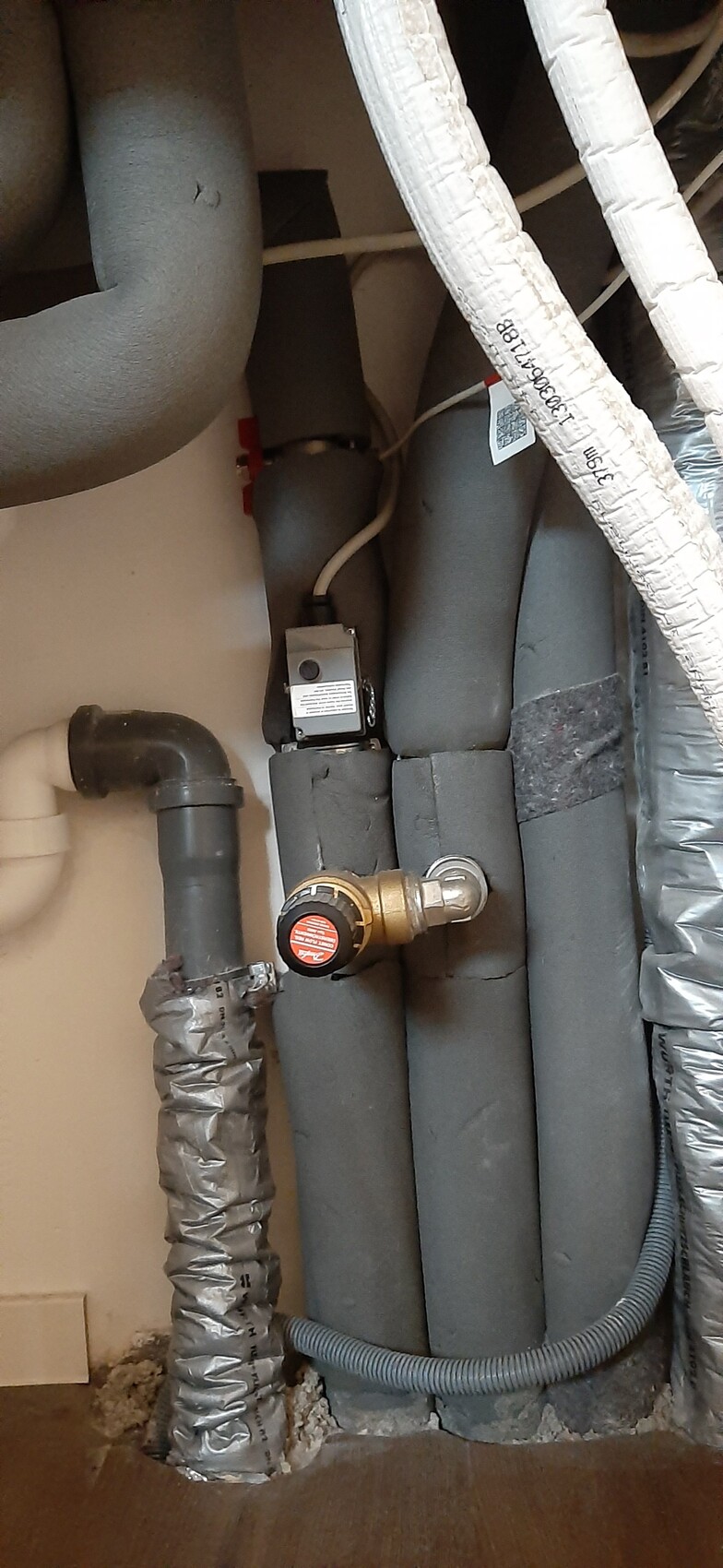 Insulated pipes and a shut-off valve with pressure regulator in the basement area.