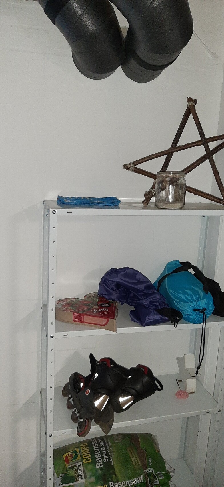 Metal shelf in basement with inline skates, bags, and lawn seed bags