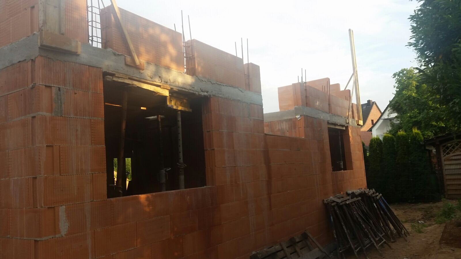 Shell of a brick house with window openings, reinforcement, and scaffolding parts.