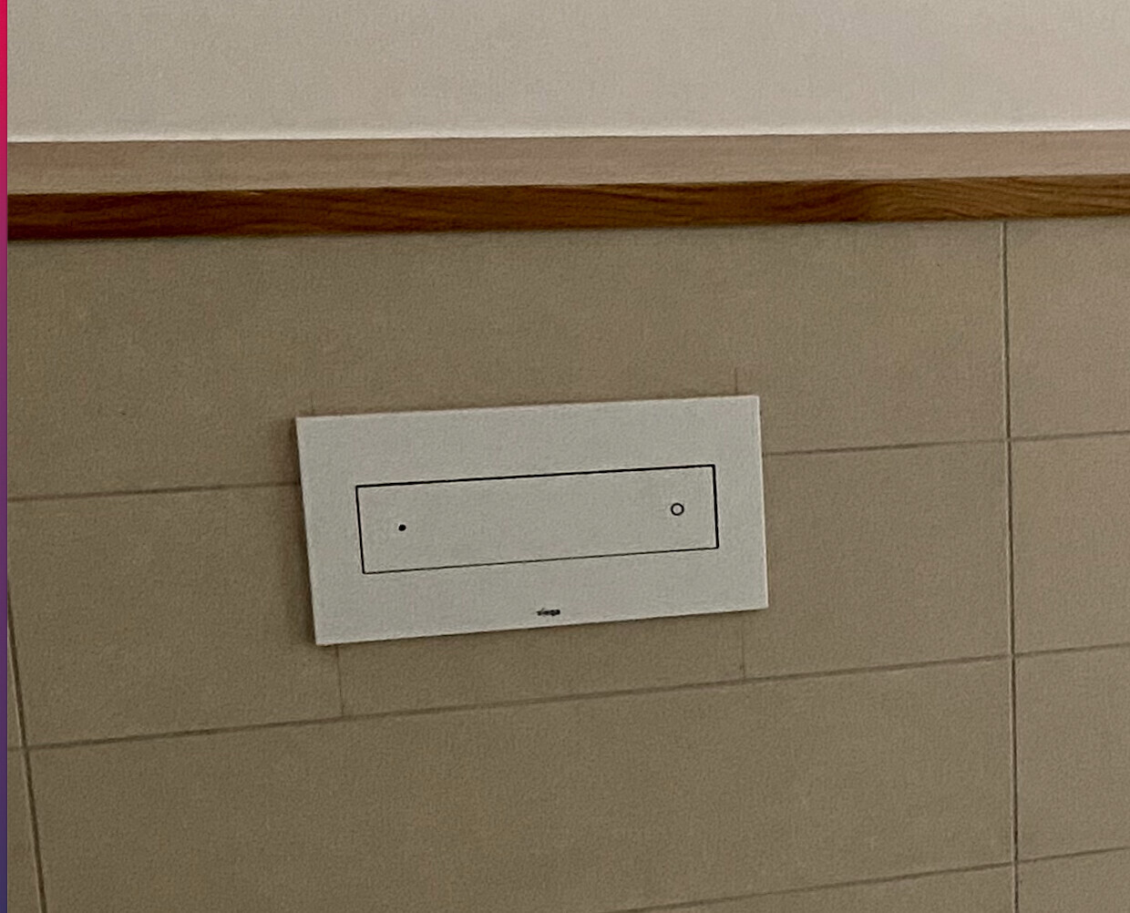 White horizontal wall panel with inner rectangle and two circles on tiled wall.