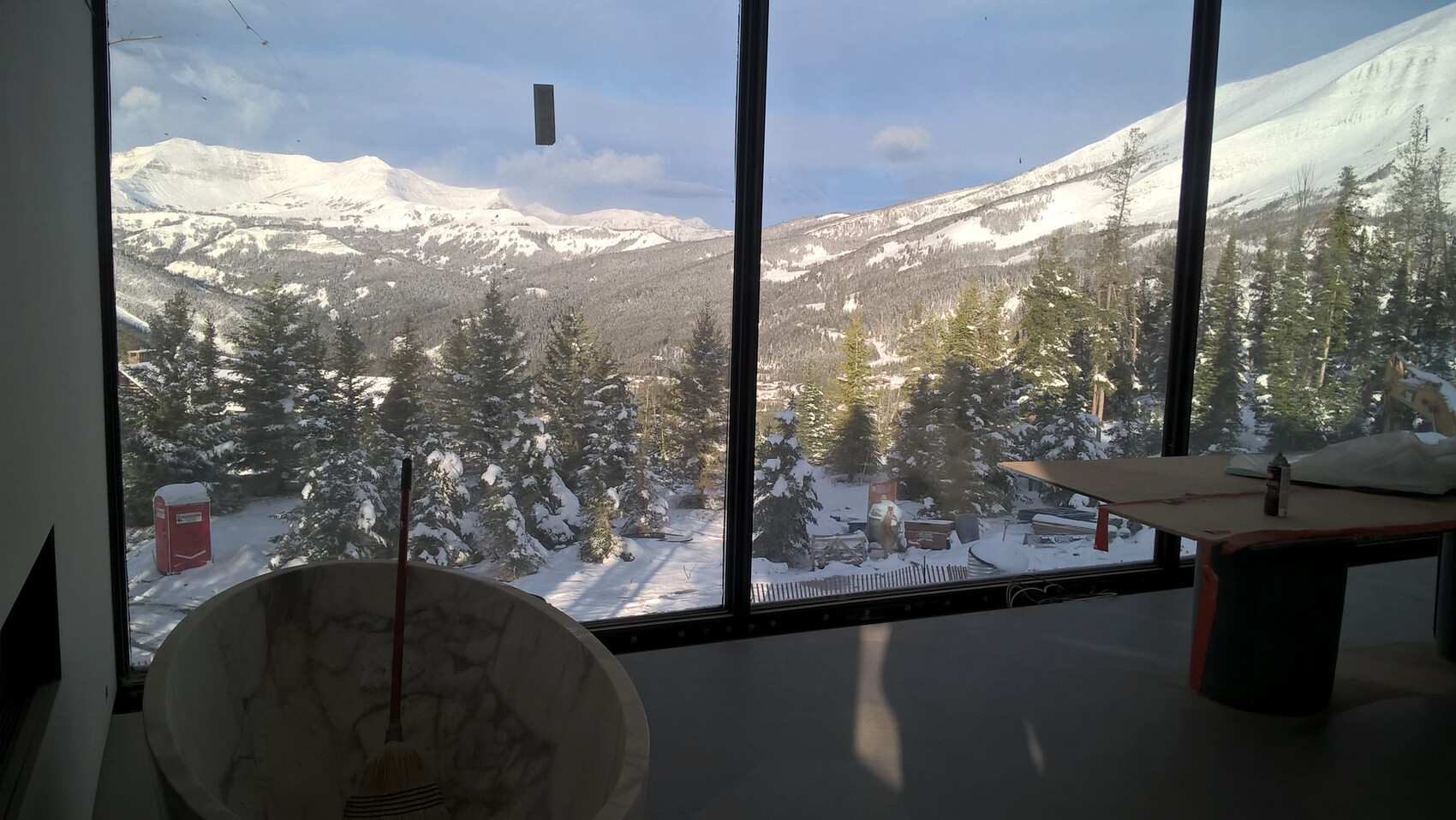 Interior with windows, view of snowy mountains; marble basin and broom in front.