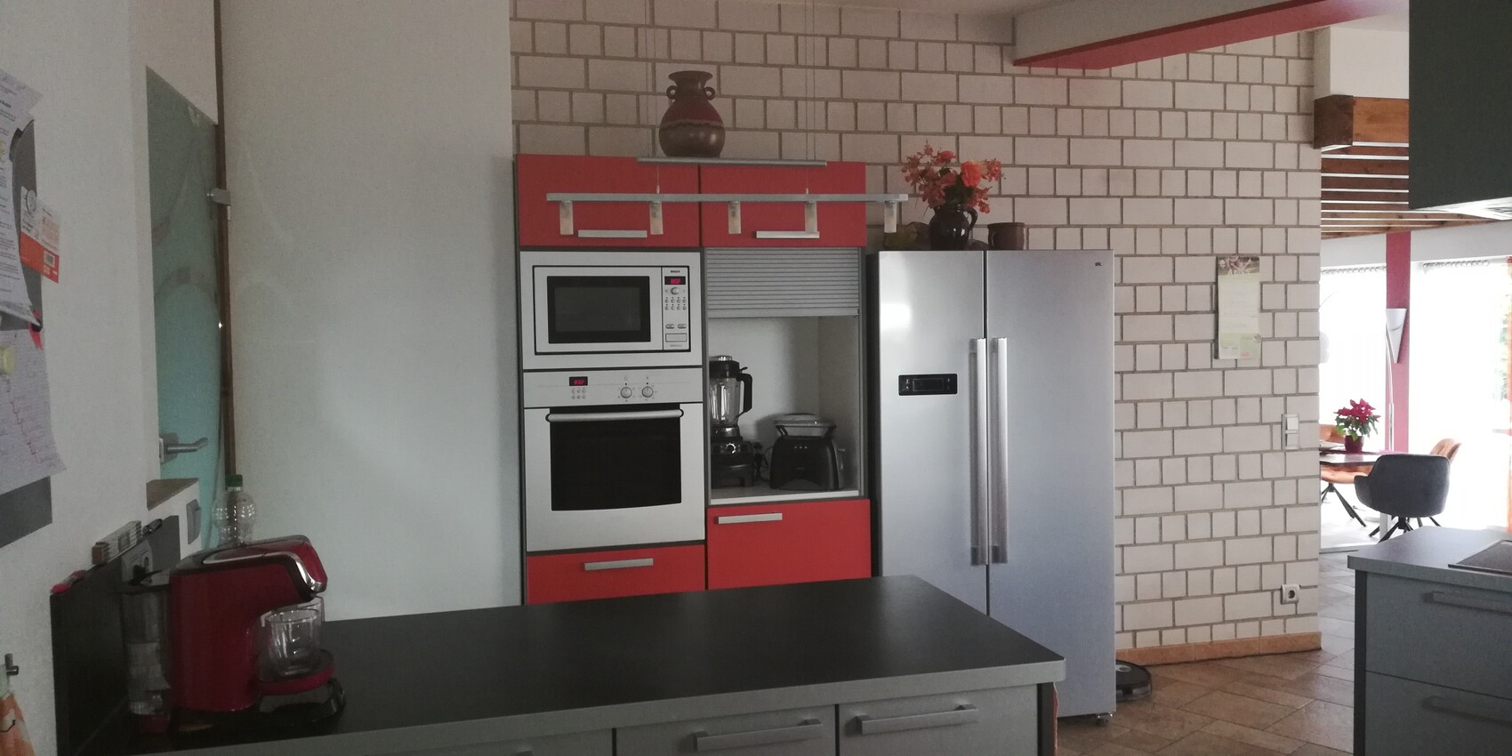 Modern kitchen with red fronts, built-in oven, microwave, refrigerator, and kitchen island.