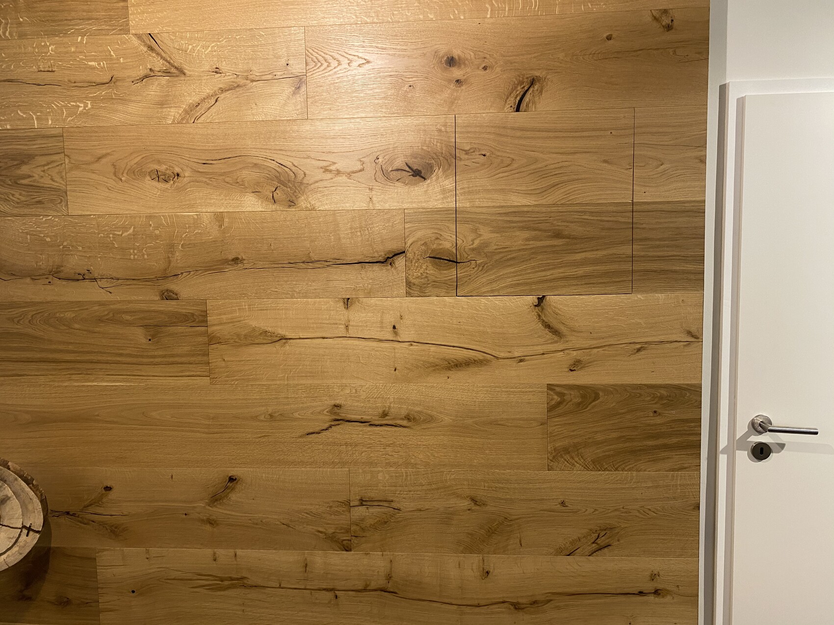 Wooden floor made of oak with grain and knots; door on the right.