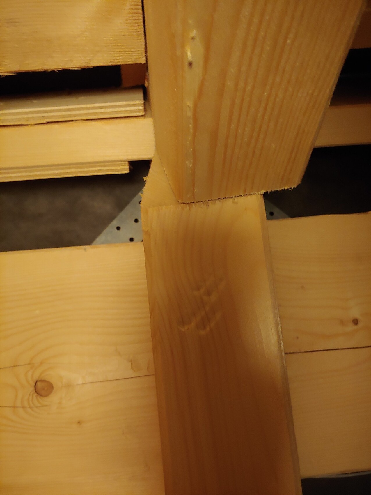 Nahaufnahme von Holzbalken: vertikaler Balken trifft auf waagerecht liegenden Balken; Sägekante sichtbar.