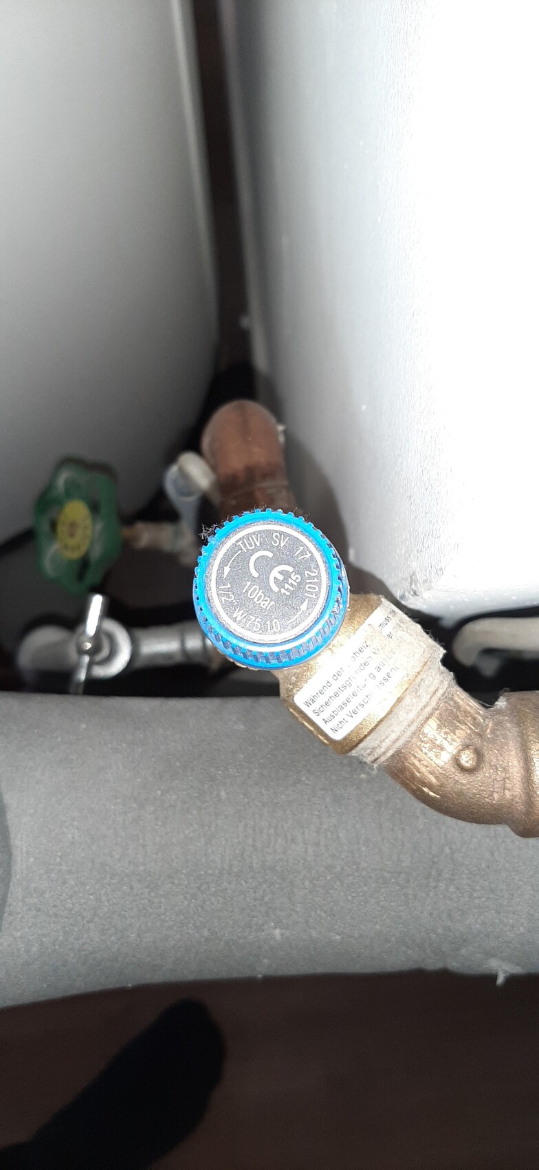 Blue knurled valve on copper pipe near wall in heating system.
