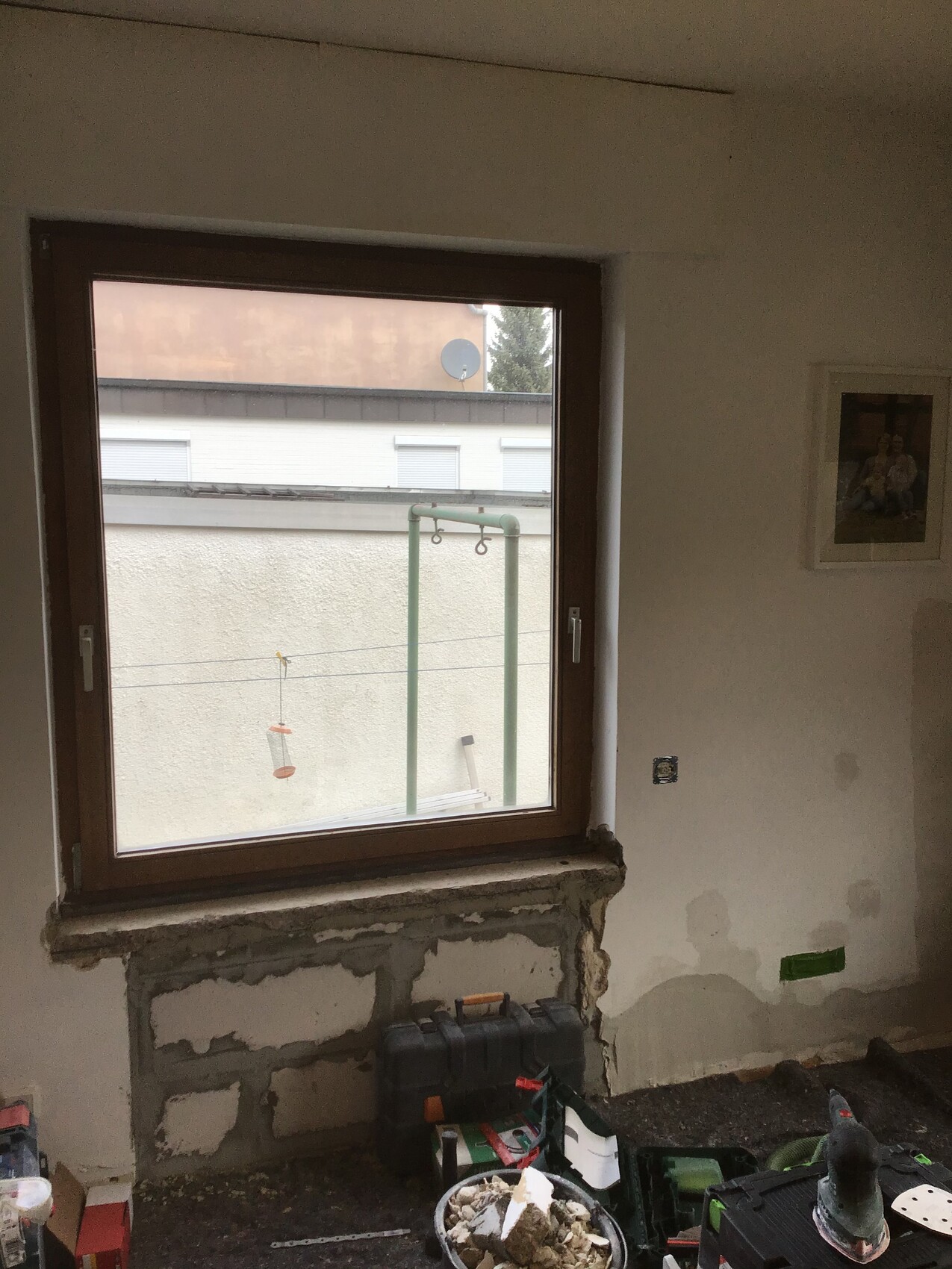 Renovierungsraum mit Fenster, Werkzeugkasten und unverputzter Wand.
