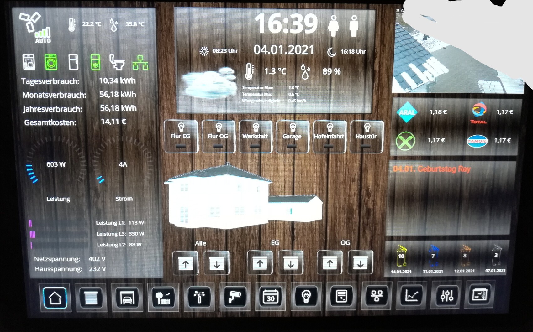 Smart home dashboard on wood texture showing time 16:39, date 04.01.2021, and energy consumption