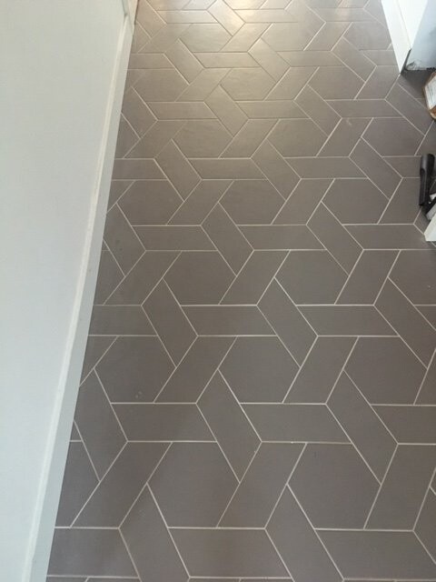 Grey hallway floor with geometrically arranged zigzag tiles.