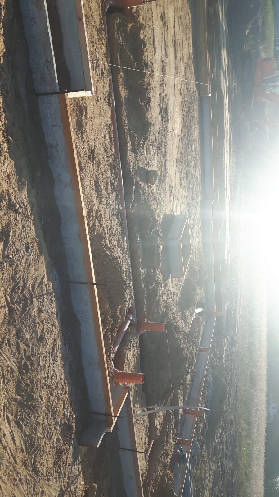 Construction site with foundations, timber framing, and shell components in the ground