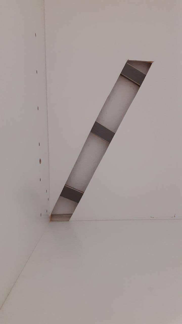 Angled slit in a white wall with metal strip and interior.