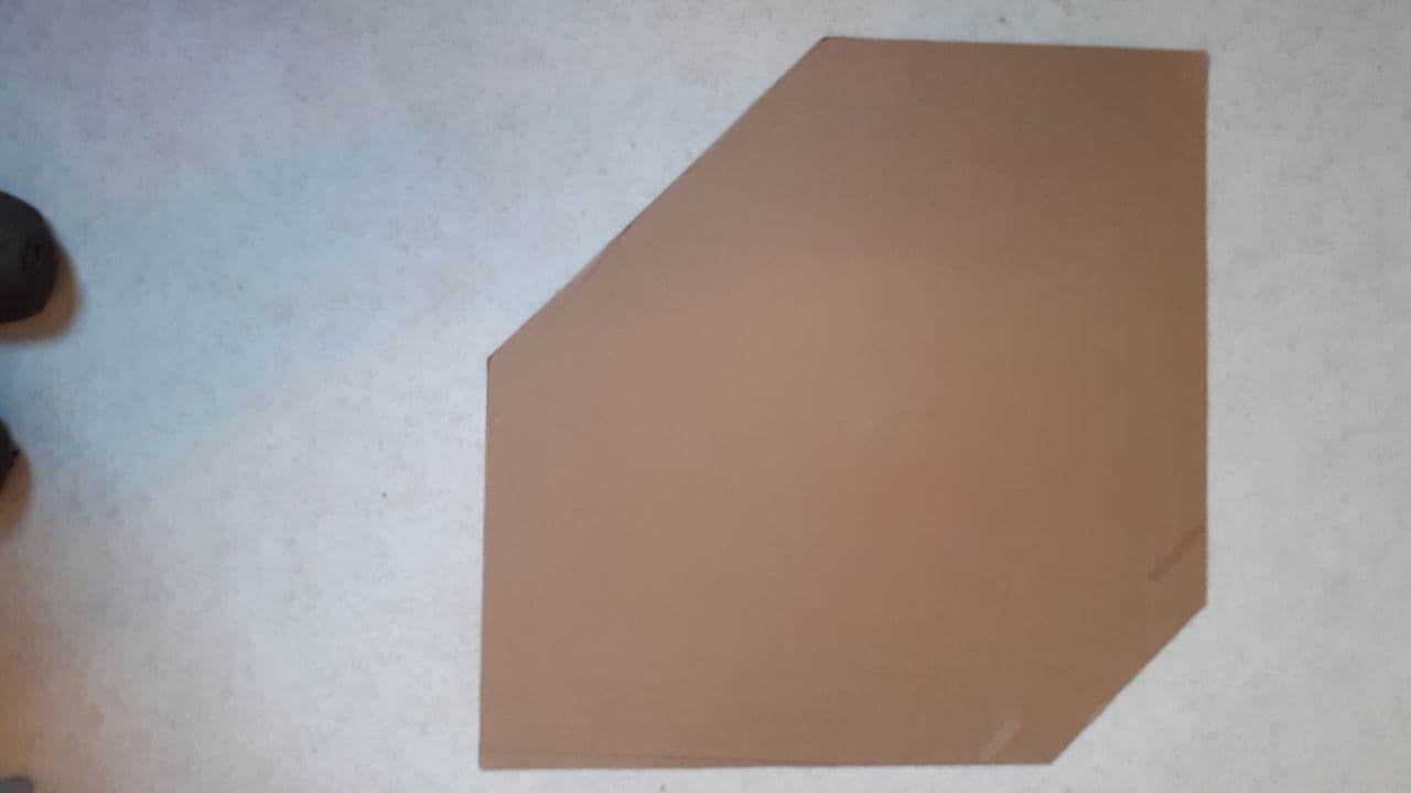 Irregular brown cardboard piece lying on a light floor