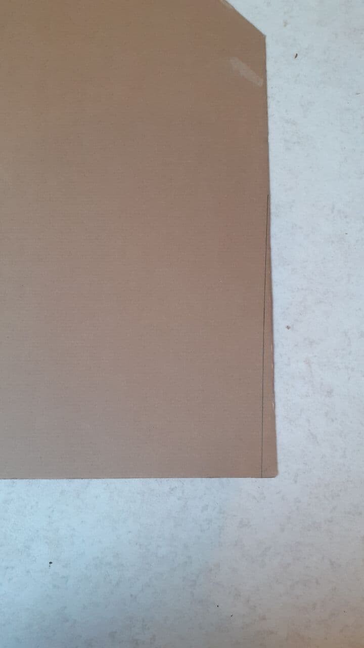 Brown cardboard piece lying flat on a light concrete floor.