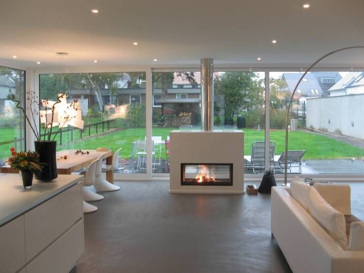 Modern open living area with fireplace and large glass front overlooking the garden, white furniture
