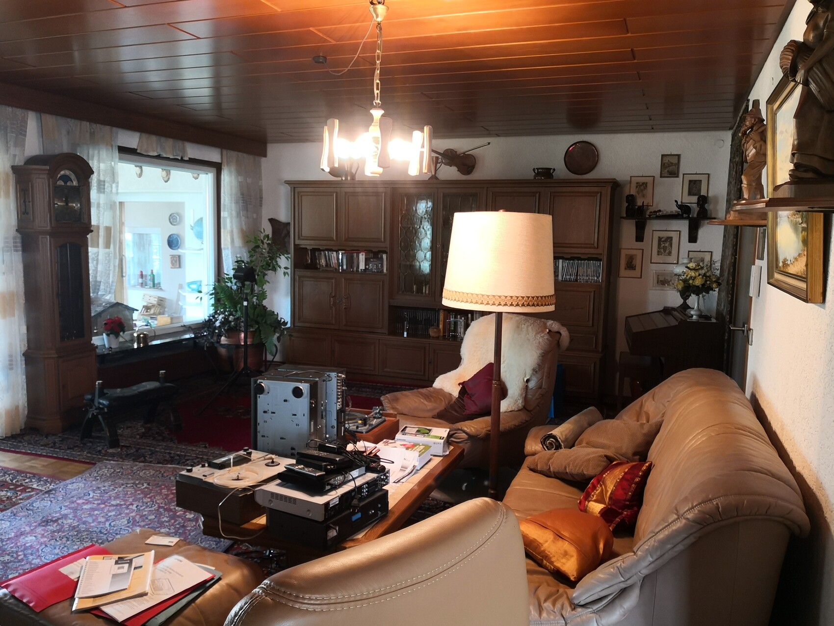 Cozy living room with leather sofa, wooden furniture, rug and electronics on the coffee table.