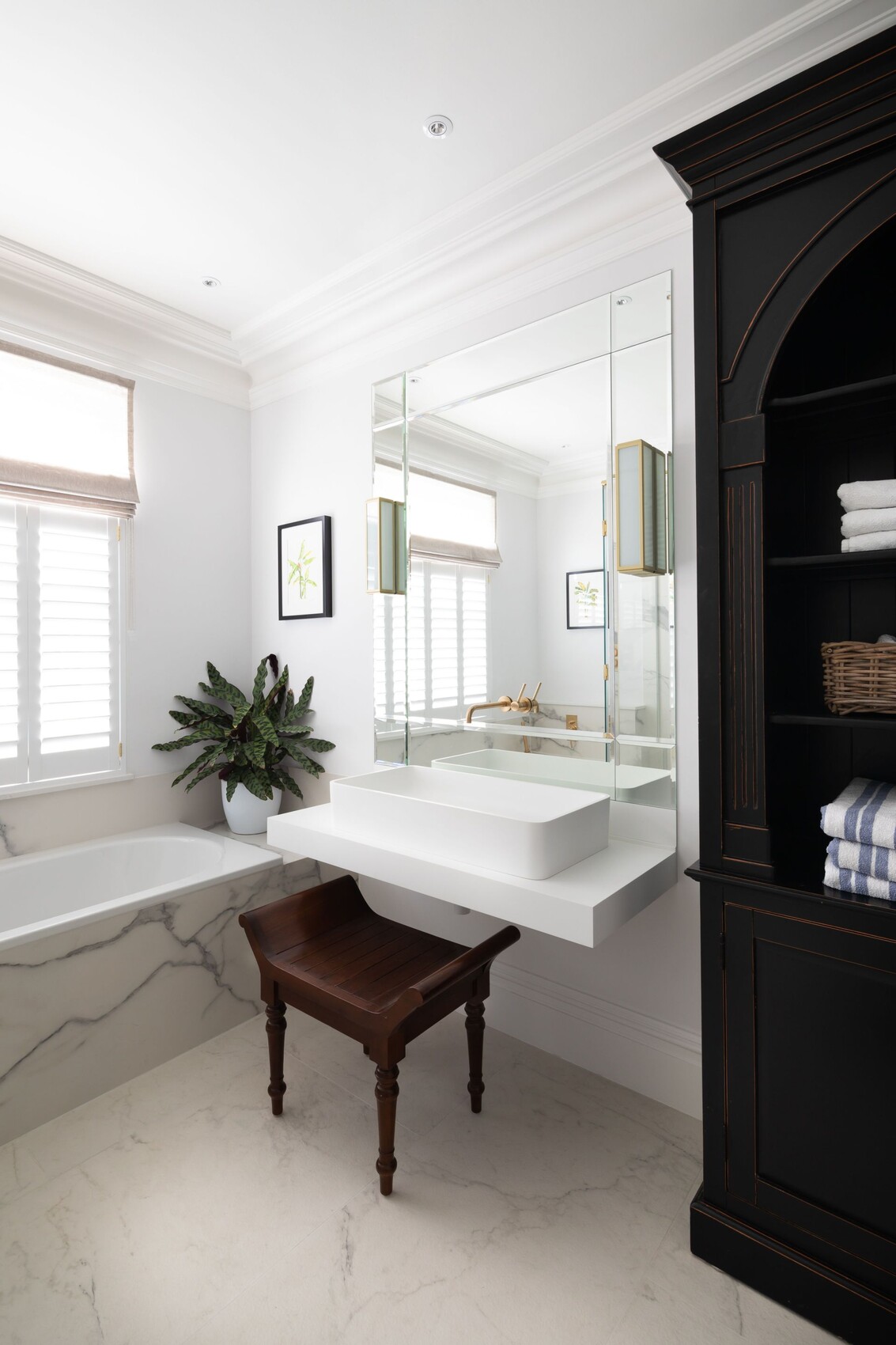 Modern bathroom: white faucet, large mirror, marble bathtub, plant