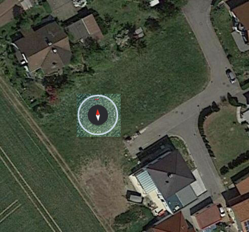 Aerial photo of house with garden and street; compass marker shows plot location.