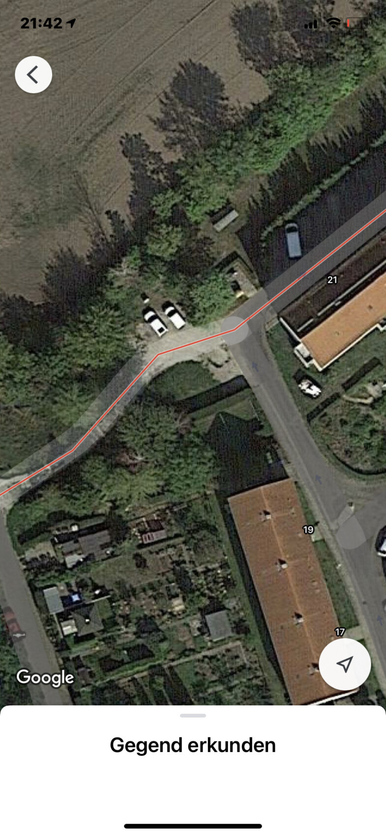 Aerial photo of a neighborhood: Curvy street, red route line, parked cars, houses and gardens.