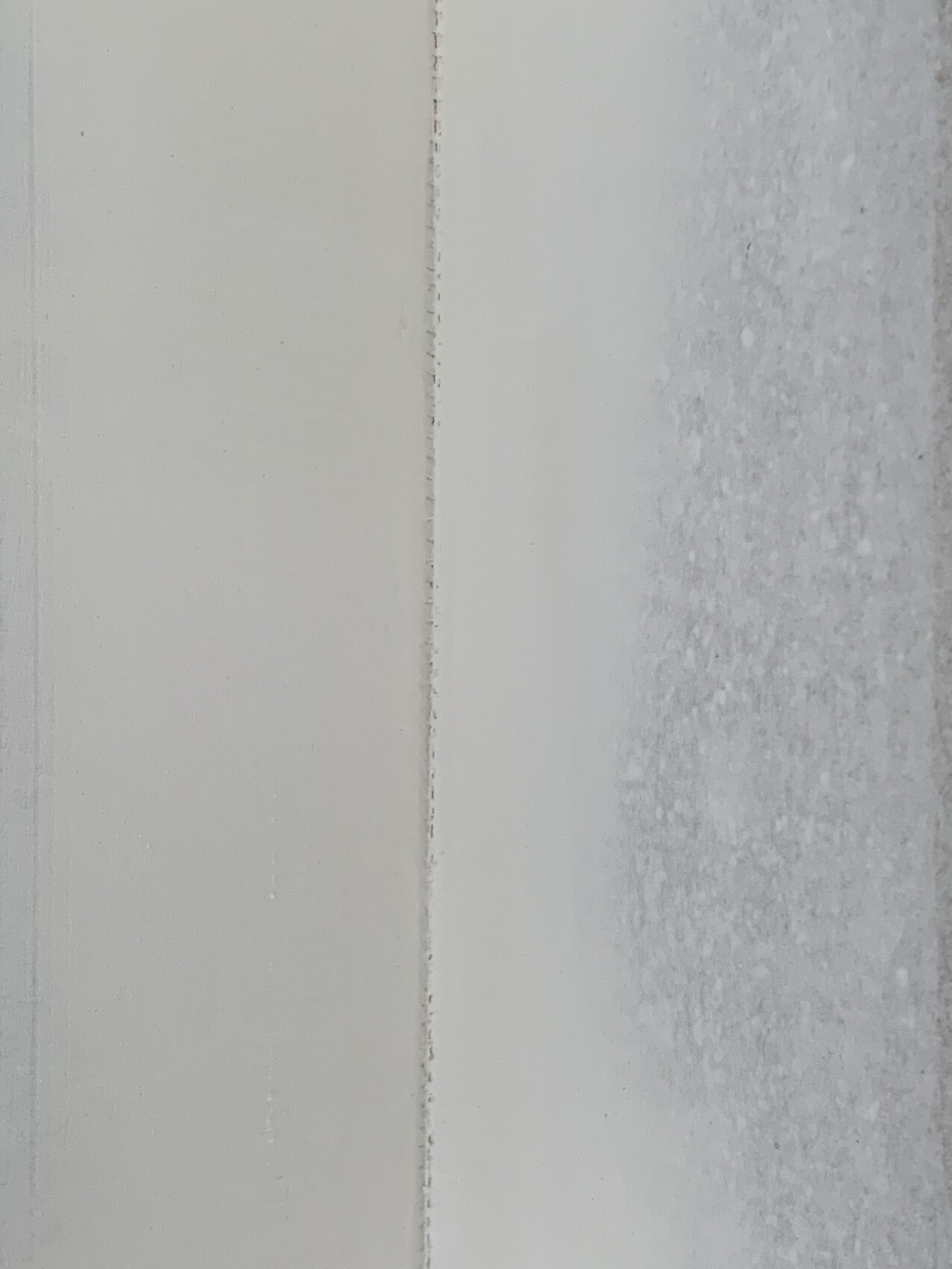 Close-up of a white door frame with a narrow joint; right side frosted glass.