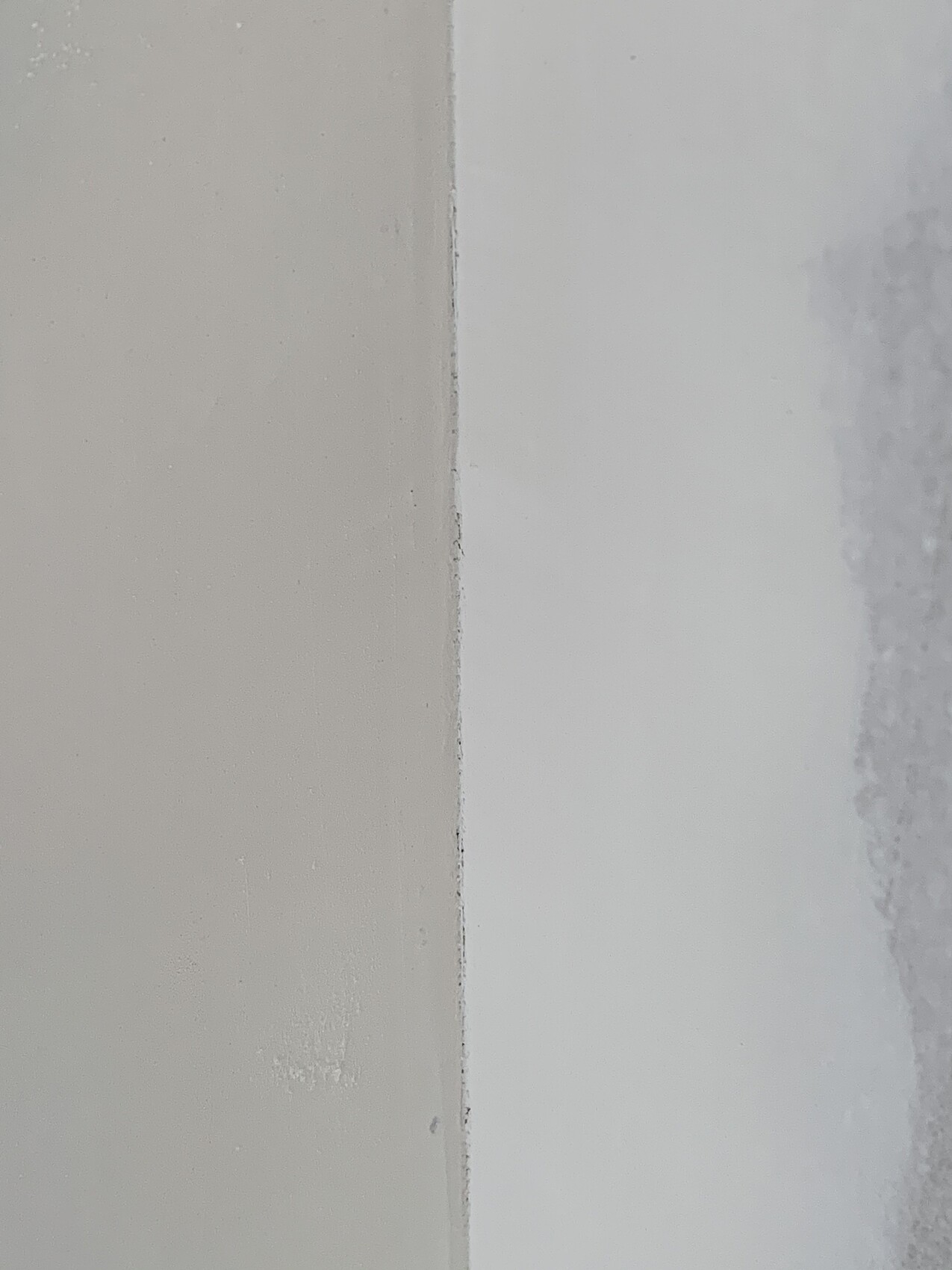 Wall joint between beige left surface and white right surface.