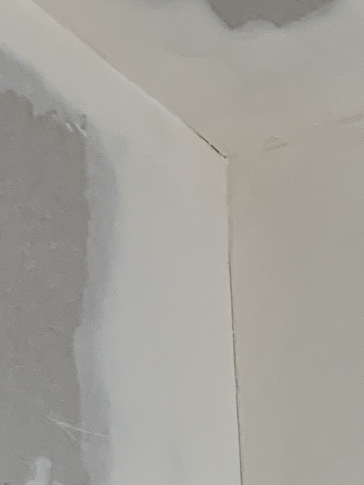 White painted interior wall and ceiling with clearly visible crack in corner.