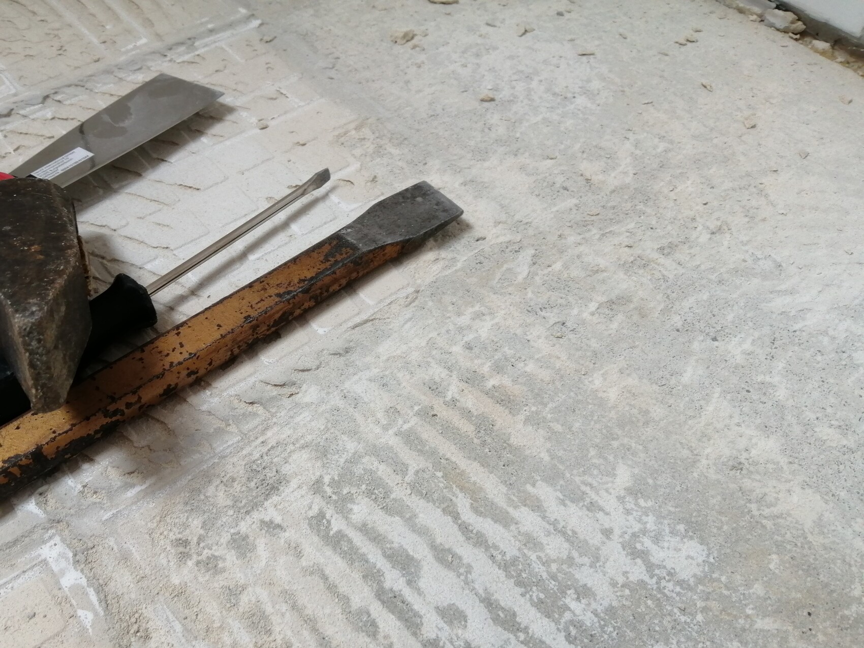 Construction site with trowel, chisel, and rusty tools on dusty floor
