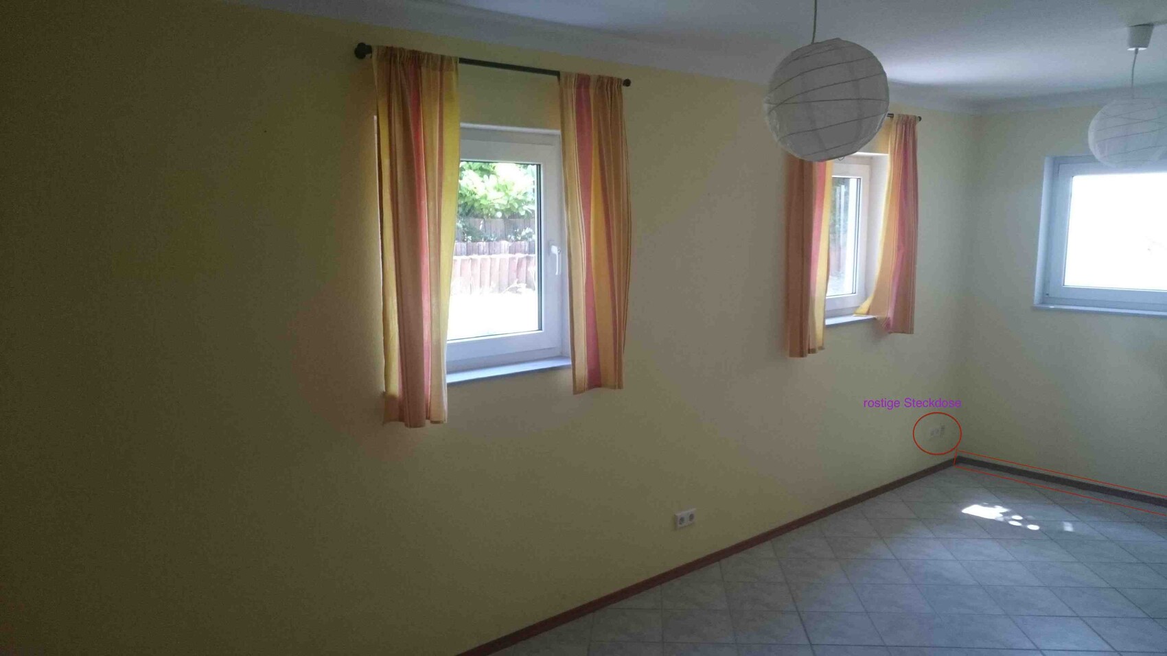 Bright living room with yellow walls, three windows with striped curtains and round paper lamps.