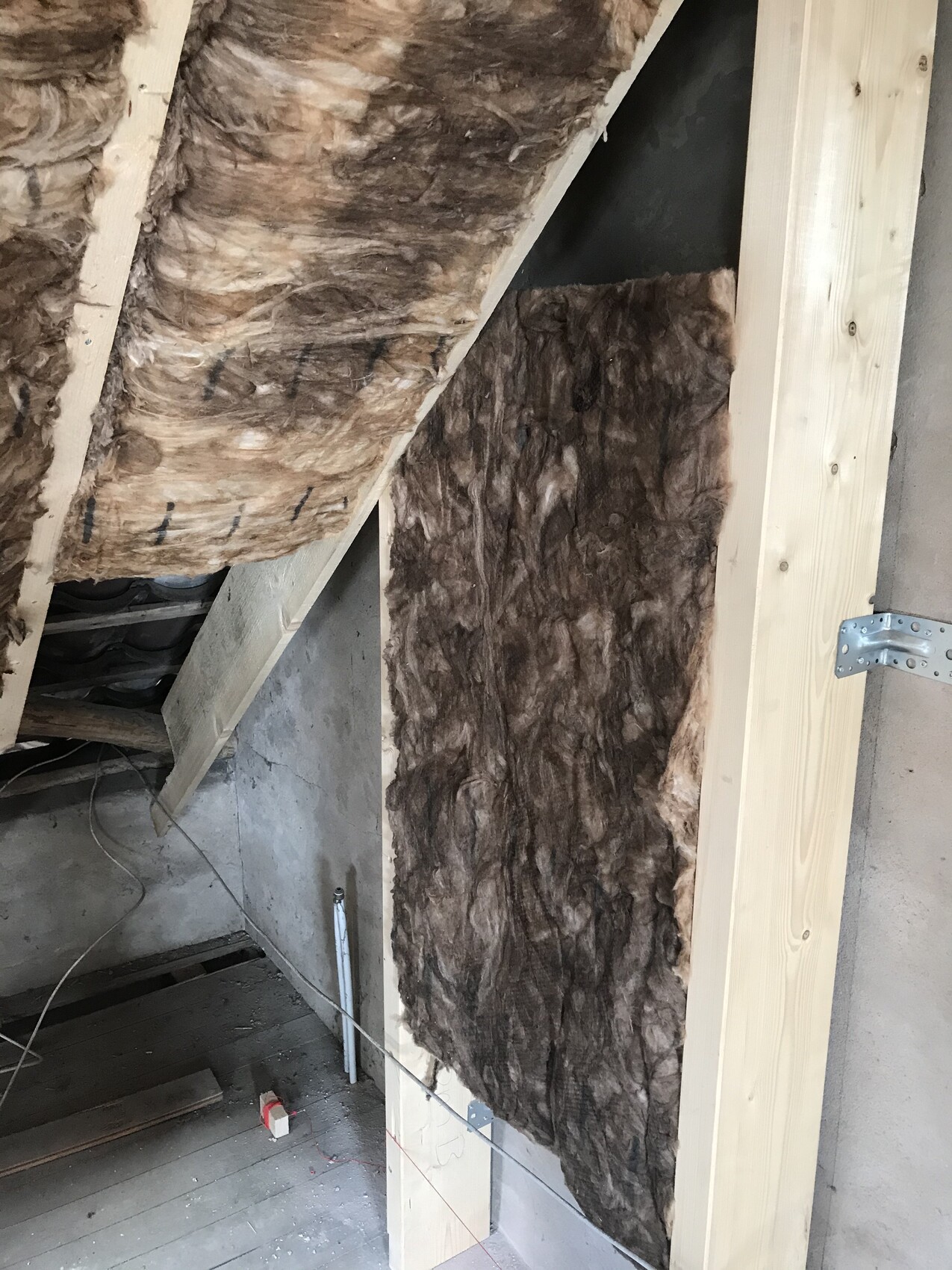 Attic wall with brown mineral wool insulation between wooden frame.