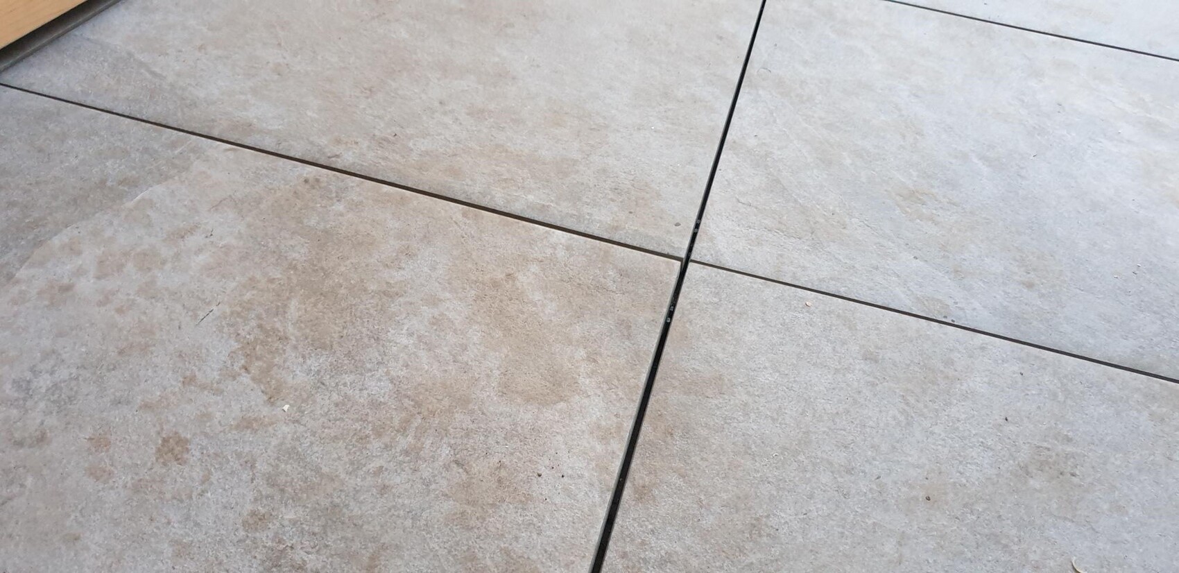 Black cable lying diagonally across light gray tiled floor.