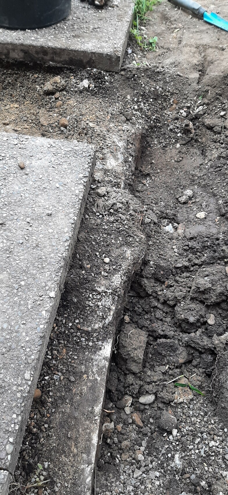 Excavated pit next to concrete step on construction site with loose soil