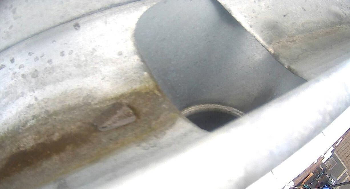 Close-up of a rusty drainpipe with rust spots on metal surface