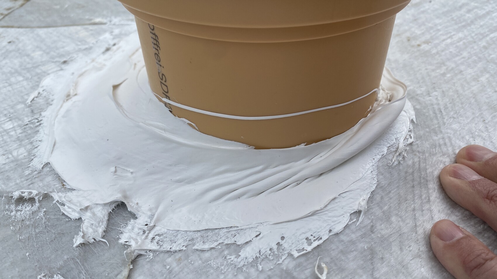 Terracotta flower pot on a surface, sealed all around with white sealing compound, close-up.