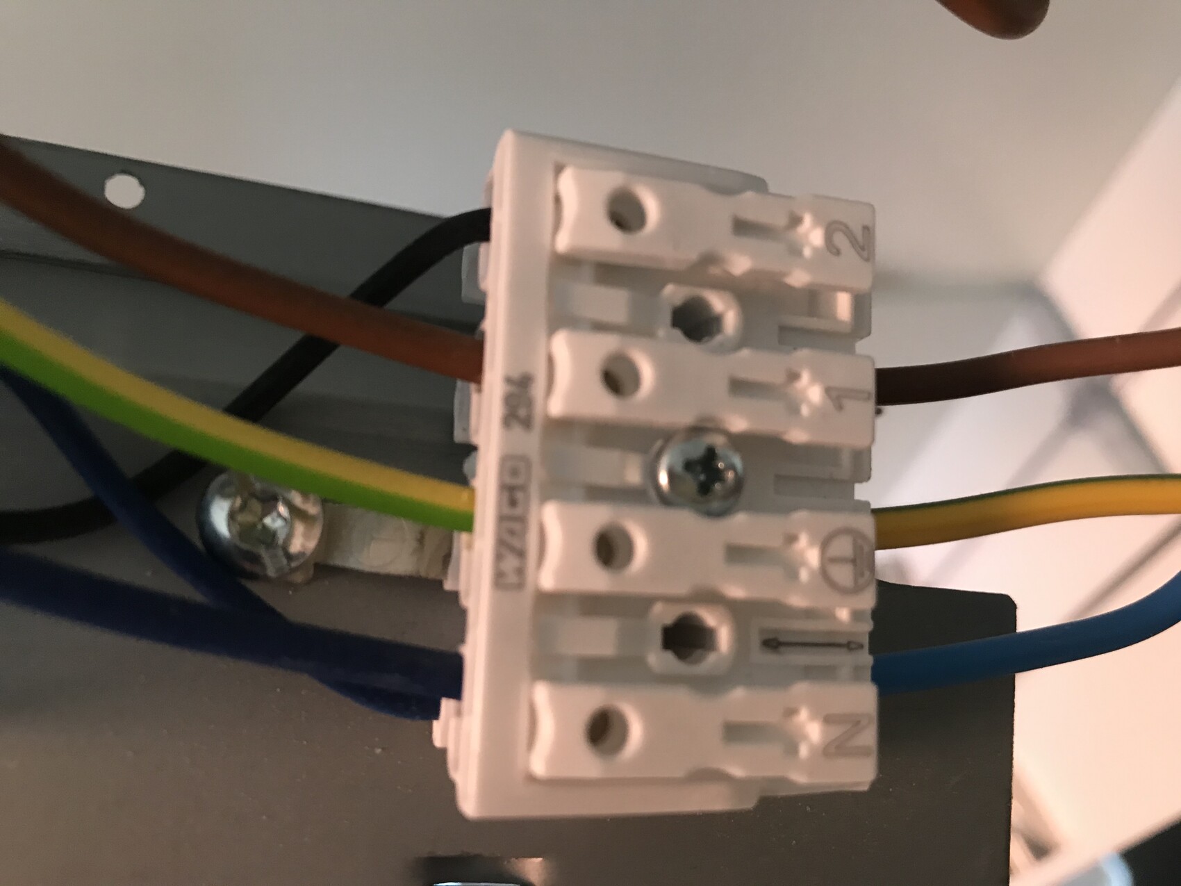 Close-up of a terminal block with brown, blue and green-yellow wires.