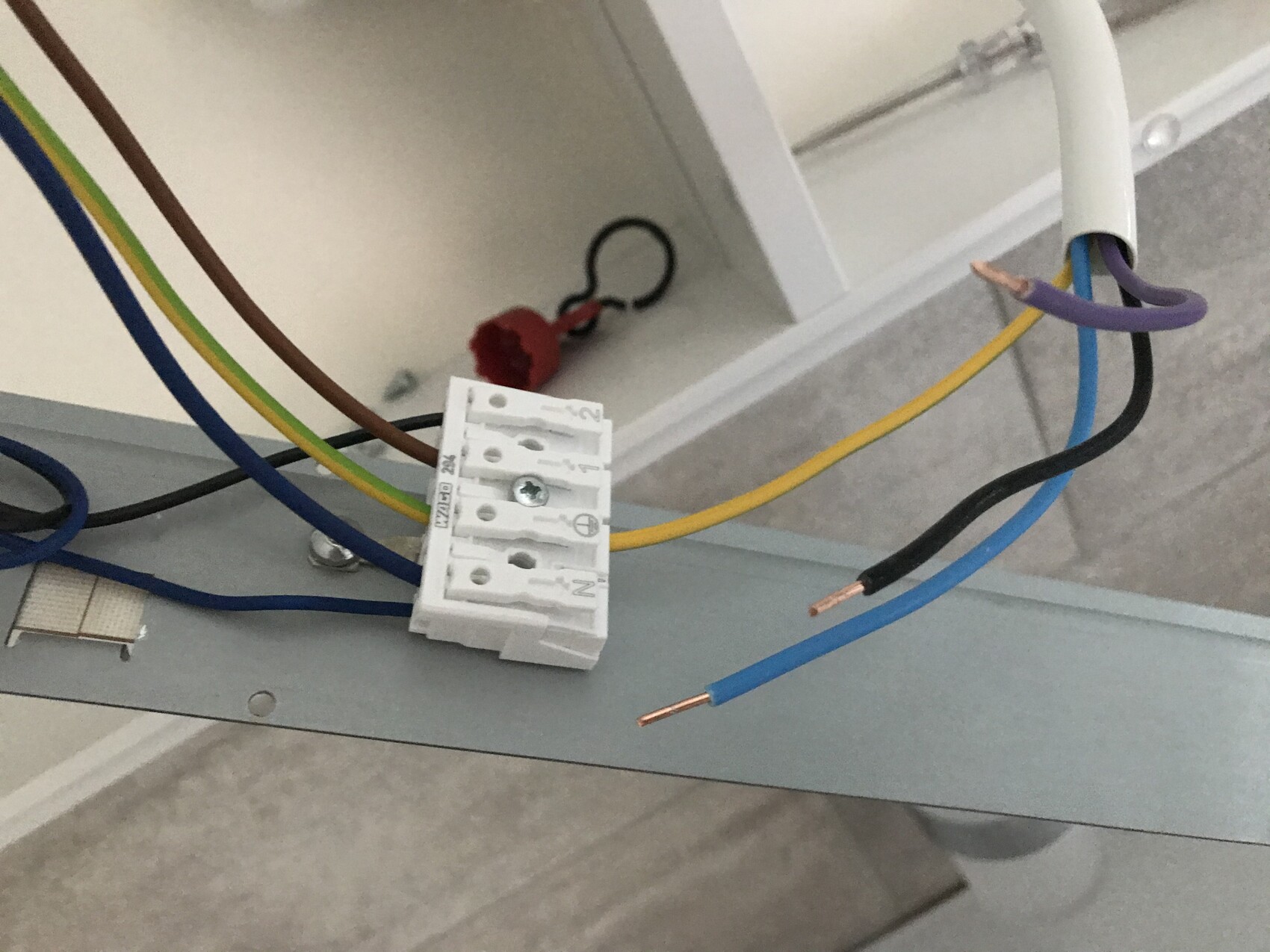 Electrical terminal block with colored wires (brown, blue, green-yellow) attached to metal frame.