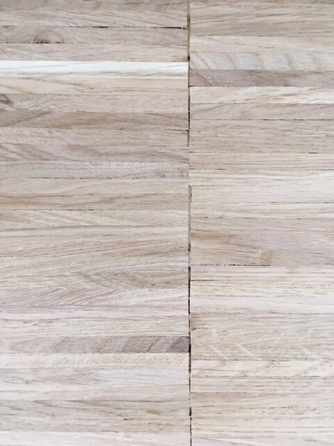 Light wooden floor with long planks and central joint in the middle of the image.