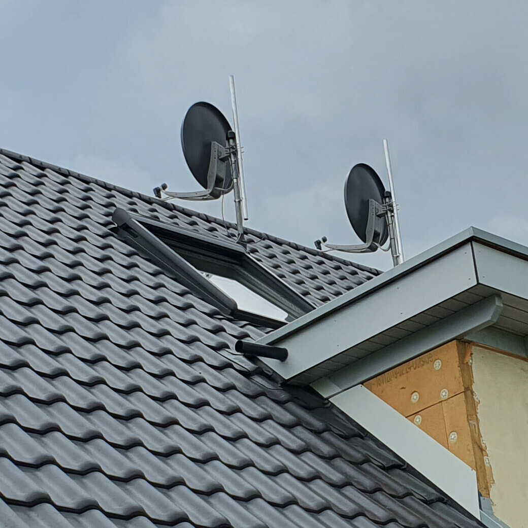 Roof with gray tiles, skylight, and two satellite dishes on the roof.