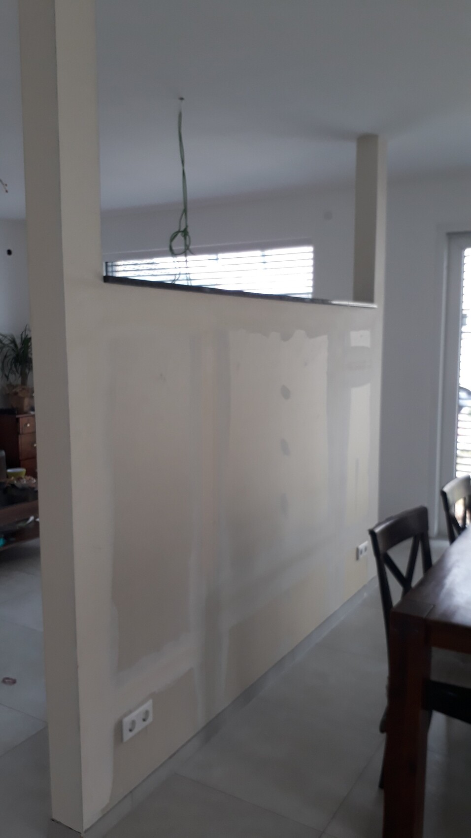 Bright living area with half partition wall, visible renovation; cables hanging from ceiling.