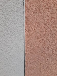 Close-up of a two-tone painted exterior wall with a vertical joint, gray on the left, peach on the right