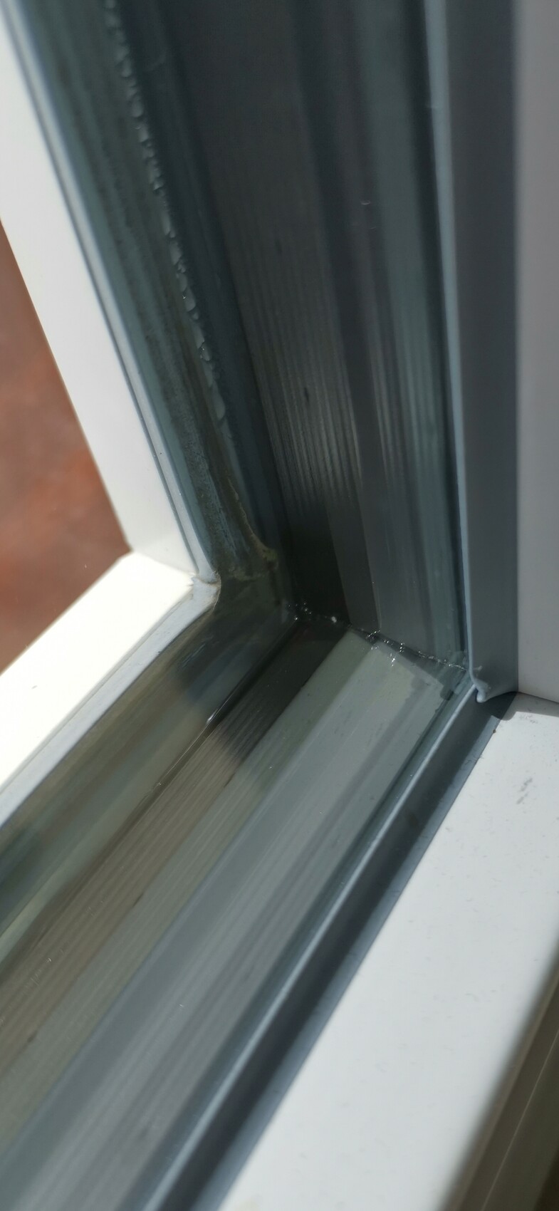 Close-up of a metal window frame with seal and glass.