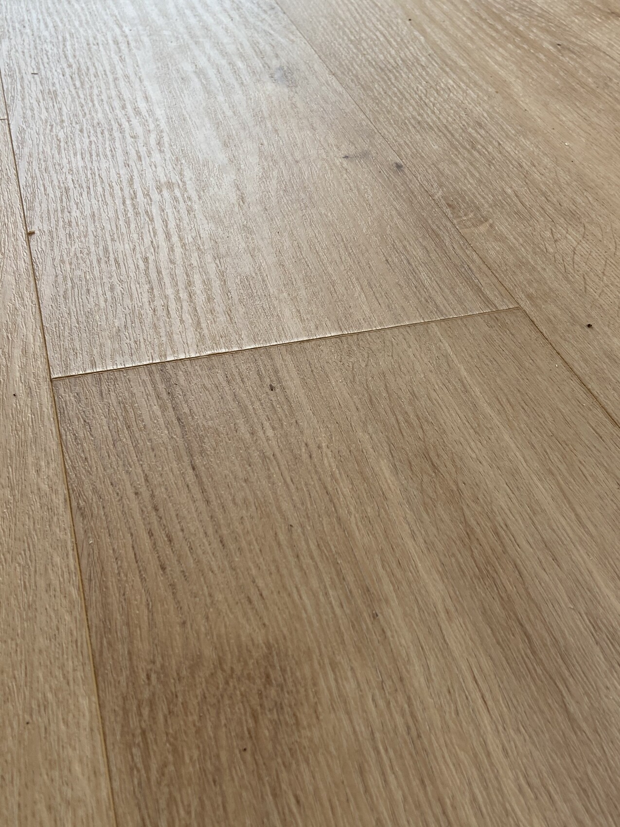 Close-up of a light brown wooden floor with visible grain and joints.