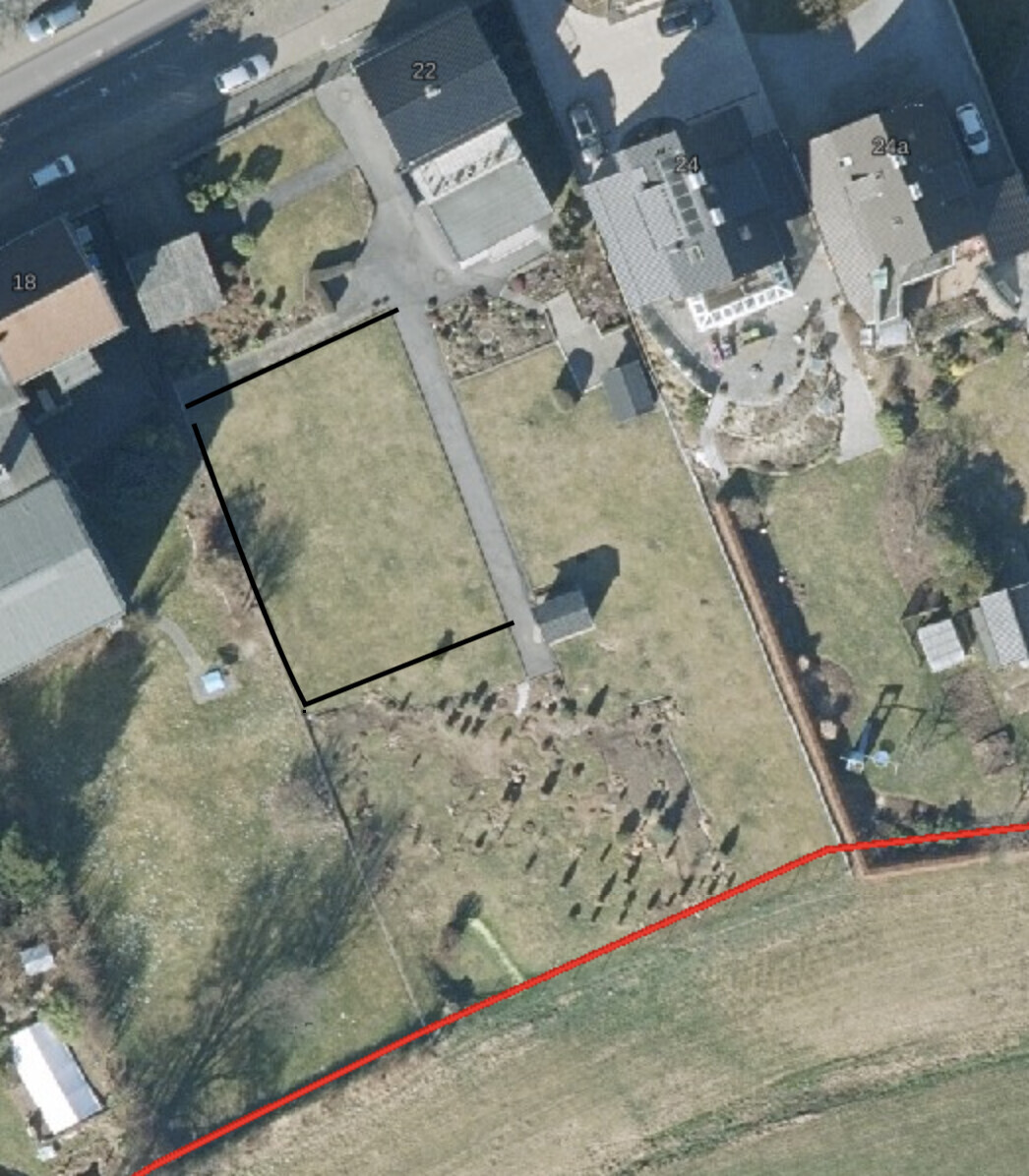 Aerial view of a residential area with adjacent cemetery, rows of graves and red outline.