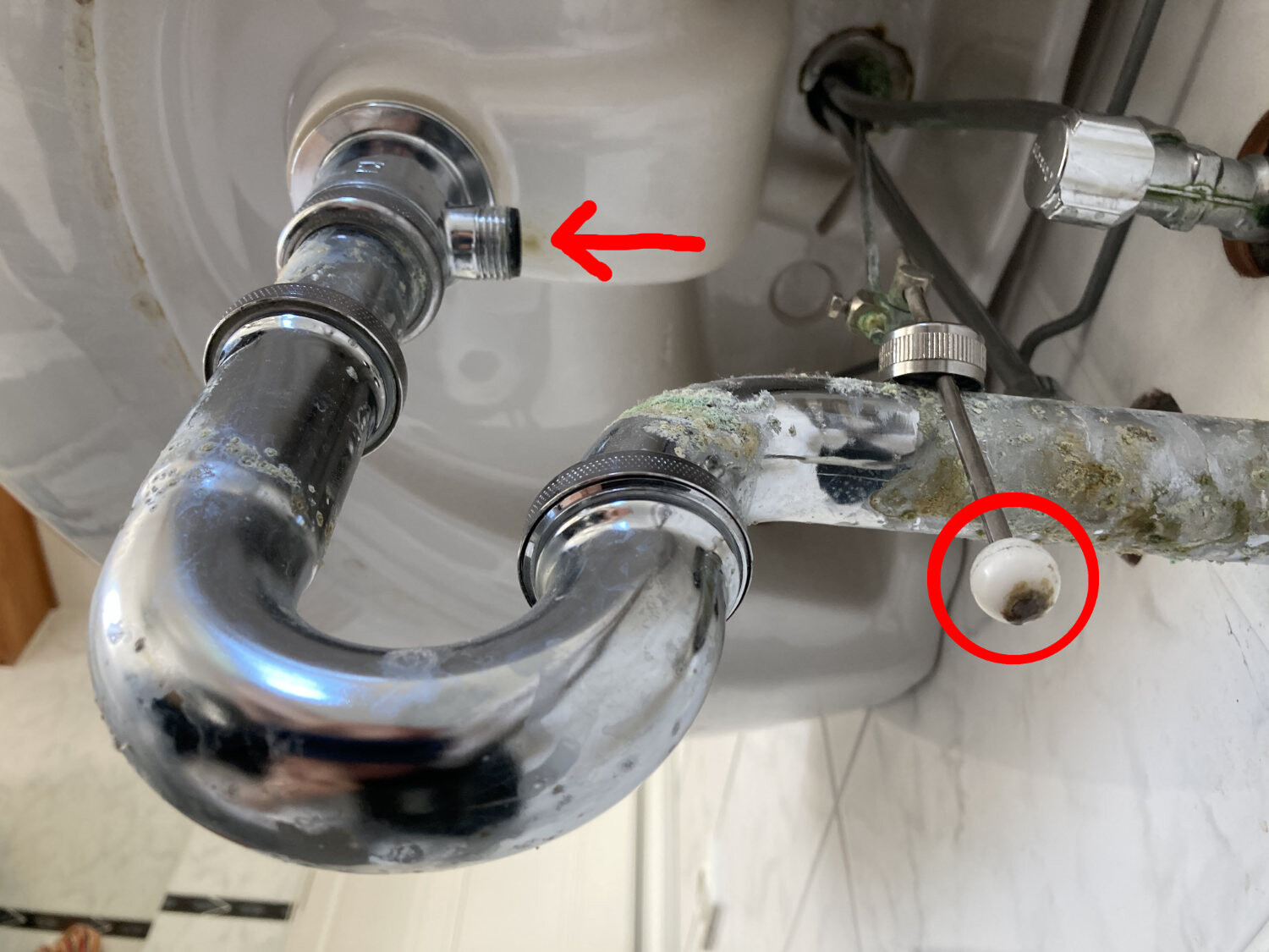 Under the sink: chrome-plated trap, rust-prone pipes; white ball with stain on the pipe.