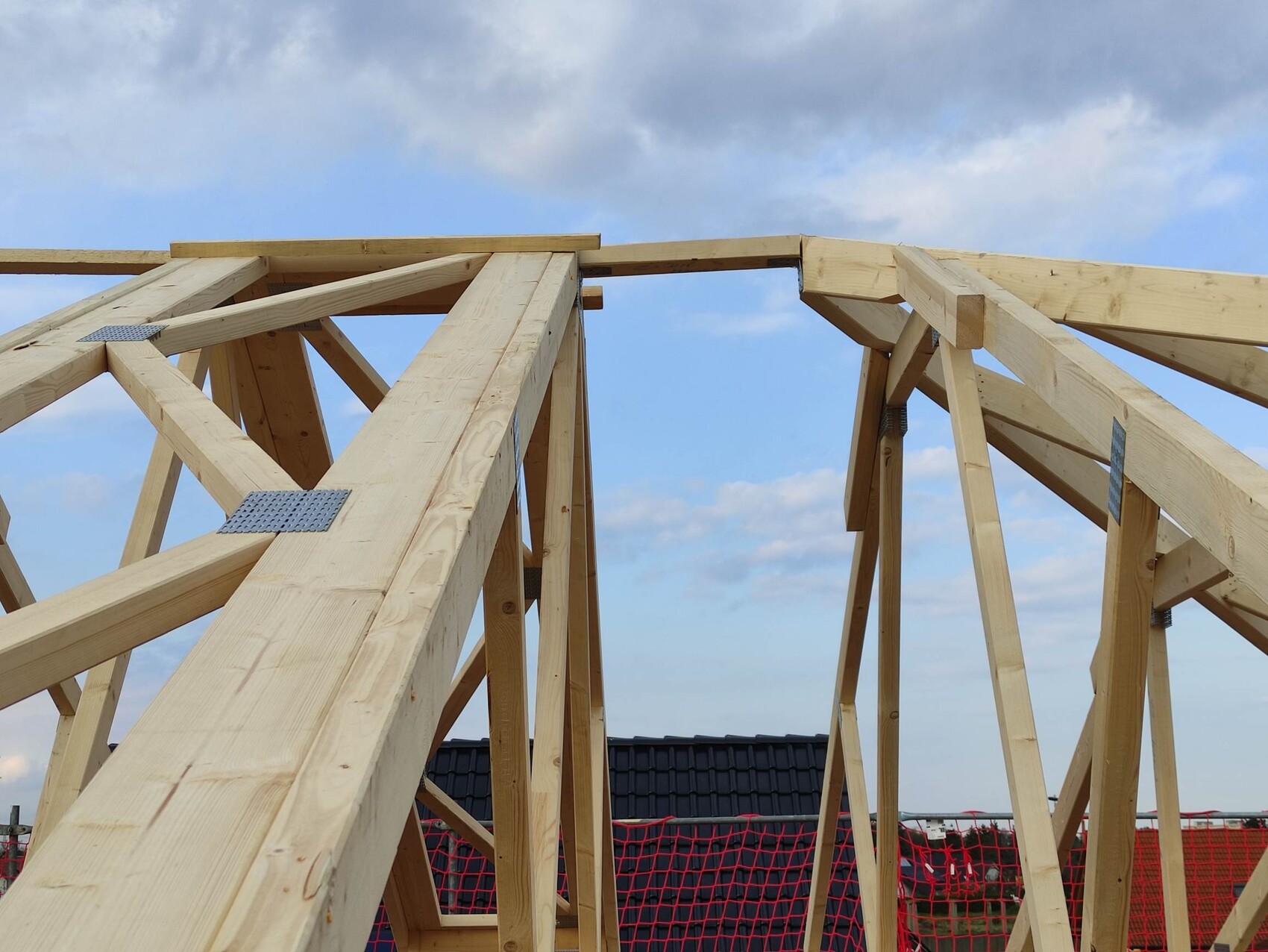 Wood roof structure with beams and metal connectors in shell construction against blue sky
