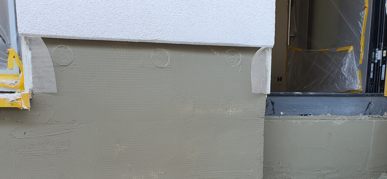 Exterior wall with insulation, plaster layer, and protective foil on the door frame